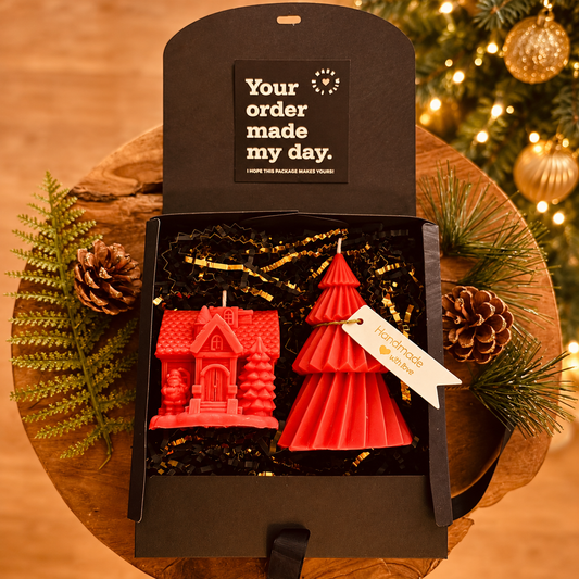 Handgemaakte rode kerstkaarsen met kersthuisje en kerstboom in geschenkdoos